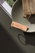 A keyring made from bronze that has been planished and engraved with the roman number symbols VIII which is the symbol for the number 8. The bronze keyring is on a moss green surface. The keyring is made by Empire Copper.