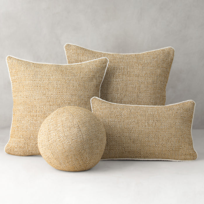 Three beige textured pillows and a spherical object on a light gray background