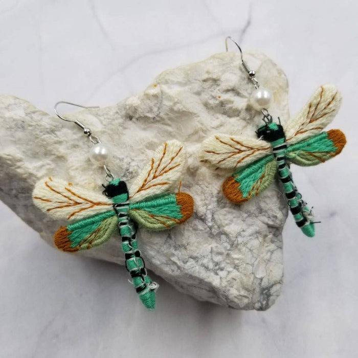 Dragonfly-shaped earrings on a textured stone surface