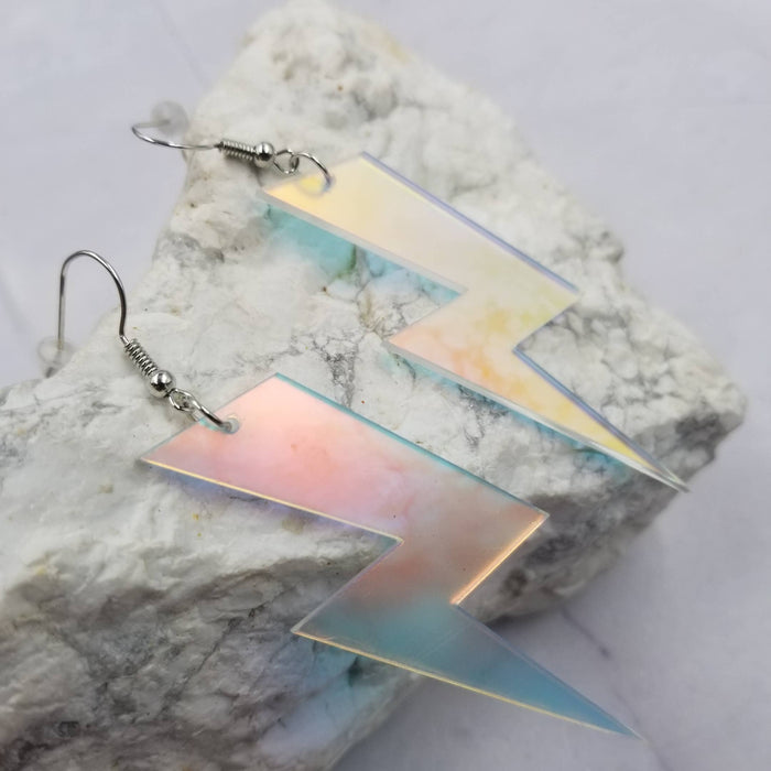Pair of lightning bolt-shaped earrings on a textured stone surface