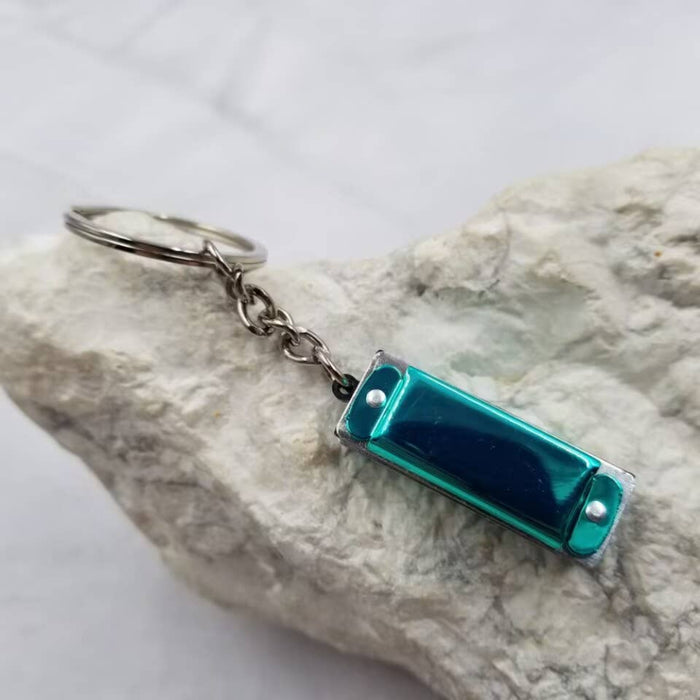 Blue harmonica-shaped keychain on a rock