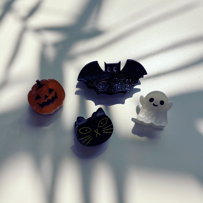 Four Halloween-themed hair clips on a light surface with shadows.