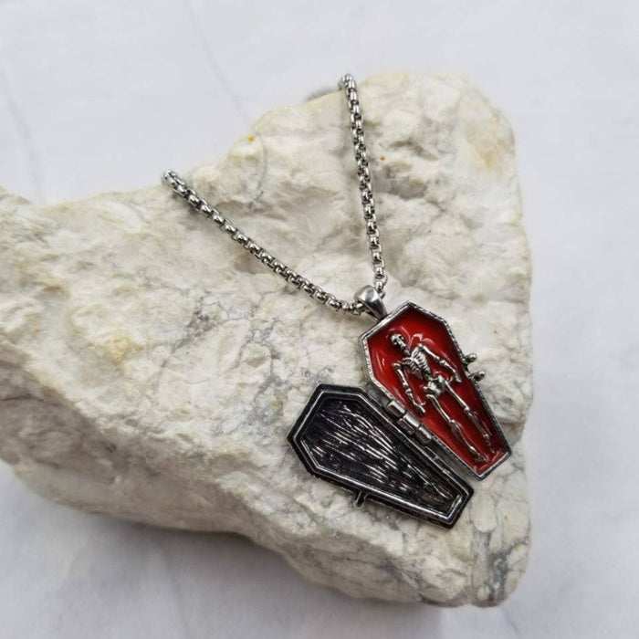 Necklace with coffin and skeleton pendant on a rock